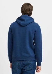 Felpa blu navy realizzata in tessuto morbido, con cappuccio regolabile, polsini a costine e una superficie liscia sul retro.
