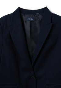 Blazer blu navy con revers a risvolto, chiusura con un solo bottone e taschino sul petto discreto. Tessuto morbido con fodera interna liscia. Etichetta del marchio visibile.
