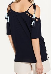 Marineblaues Cold-Shoulder-Top mit Häkeldetail und Quasten an den Trägern. Mit kurzen Ärmeln und lockerem Schnitt. Leichter Stoff.