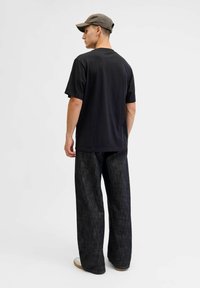 Must mustre, millel on lühikesed varrukad, kombineeritud tume denimist laia säärega pükstega, mis näitavad juhuslikku stiili. Iseloomulik lihtsus ja puhtad jooned.