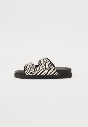 Zebra-mønstrede badesandaler med flad sort sål, med to justerbare stropper med spænder og en glat teksturoverflade.