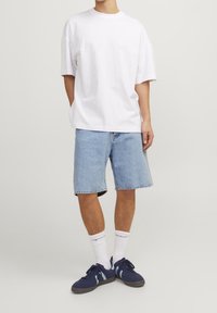 Vit oversized t-shirt, ljusblå denimshorts, vita strumpor och marinblå sneakers med ljusblå detaljer. Avslappnad outfit med lös passform.