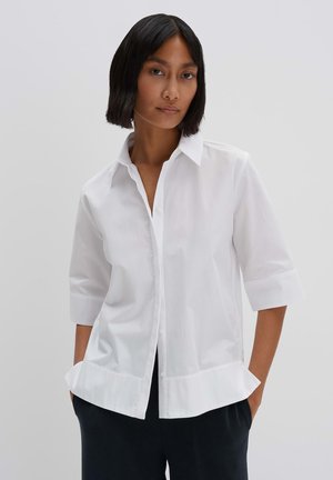 Camicia bianca con colletto, maniche a tre quarti, orlo curvo e tessuto leggero e morbido.