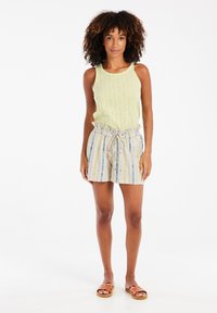 Débardeur sans manches jaune clair avec motif texturé, associé à un short rayé avec taille réglable par cordon. Des sandales marron complètent la tenue.