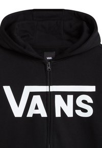 Black zip-up hoodie with a large white "VANS" logo on the front. Features a hood and smooth fabric texture. Zipper closure at the front.