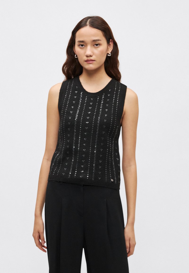 Crni top bez rukava od pletenog materijala s teksturiranim uzorkom i srebrnim naglascima te okruglim izrezom na vratu. Dizajniran s prilagođenim krojem.