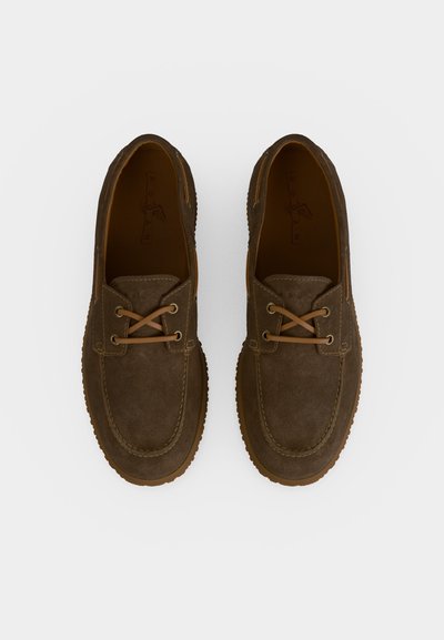 Paire de chaussures style mocassin en daim marron avec des lacets en cuir beige, vue de dessus sur fond blanc.