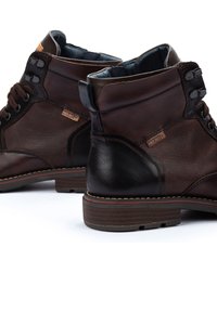 Brown leather ankle boots with textured brown mesh panels, black accents, round toe, and a durable rubber sole. Stitched detailing along the edge.