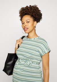 Vestido riscado em verde menta, branco e azul-marinho. Mangas curtas, design evasê, cintura presa com um laço, combinado com uma mala tote preta. Textura de tecido suave.