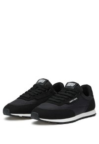 Sneaker sportive nere con un mix di materiali lisci e strutturati, design con lacci e suola bianca a contrasto. Etichetta del marchio sulla linguetta.