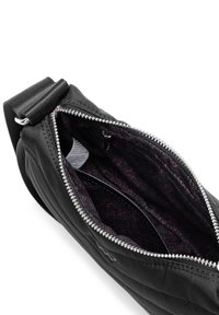 Černá nylonová taška se stříbrným zipem, s vzorovaným vnitřkem v tmavě vínové barvě a geometrickými vzory. Obsahuje nastavitelné ramenní popruhy.