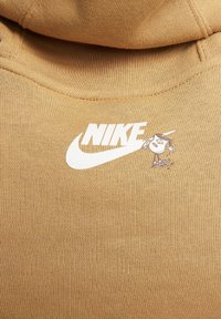 Hnědá bavlněná mikina s kapucí s bílým logem Nike a malou grafikou postavičky na levé straně. Texturovaná látka, žebrovaná kapuce.