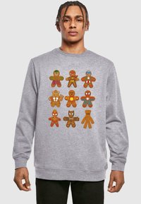 Felpa grigia con figure di pan di zenzero fantasiose in costumi da supereroe, che mostrano colori vivaci e design giocosi.