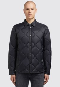 Sort pufjakke med en kviltet design, der har rundede mønstre, trykknapper og krave. Lange ærmer og sidelommer er inkluderet.