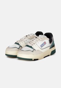 Sneakers bianchi e verdi con un design a materiali misti in suede e pelle, suola spessa e motivo a zigzag sulla punta.
