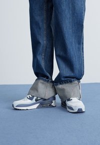 Adidași Nike Air Max în alb și bleumarin, cu un superior din plasă și materiale sintetice, vârf rotund și amortizare vizibilă pe talpă.