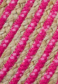 Tapis tressé rayé en fibres naturelles, avec des accents roses et rose clair, une surface texturée et des détails de couture contrastants.