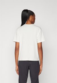 Witte katoenen t-shirt met korte mouwen, een relaxte pasvorm, ronde hals en rechte zoom, gepositioneerd tegen een effen achtergrond.