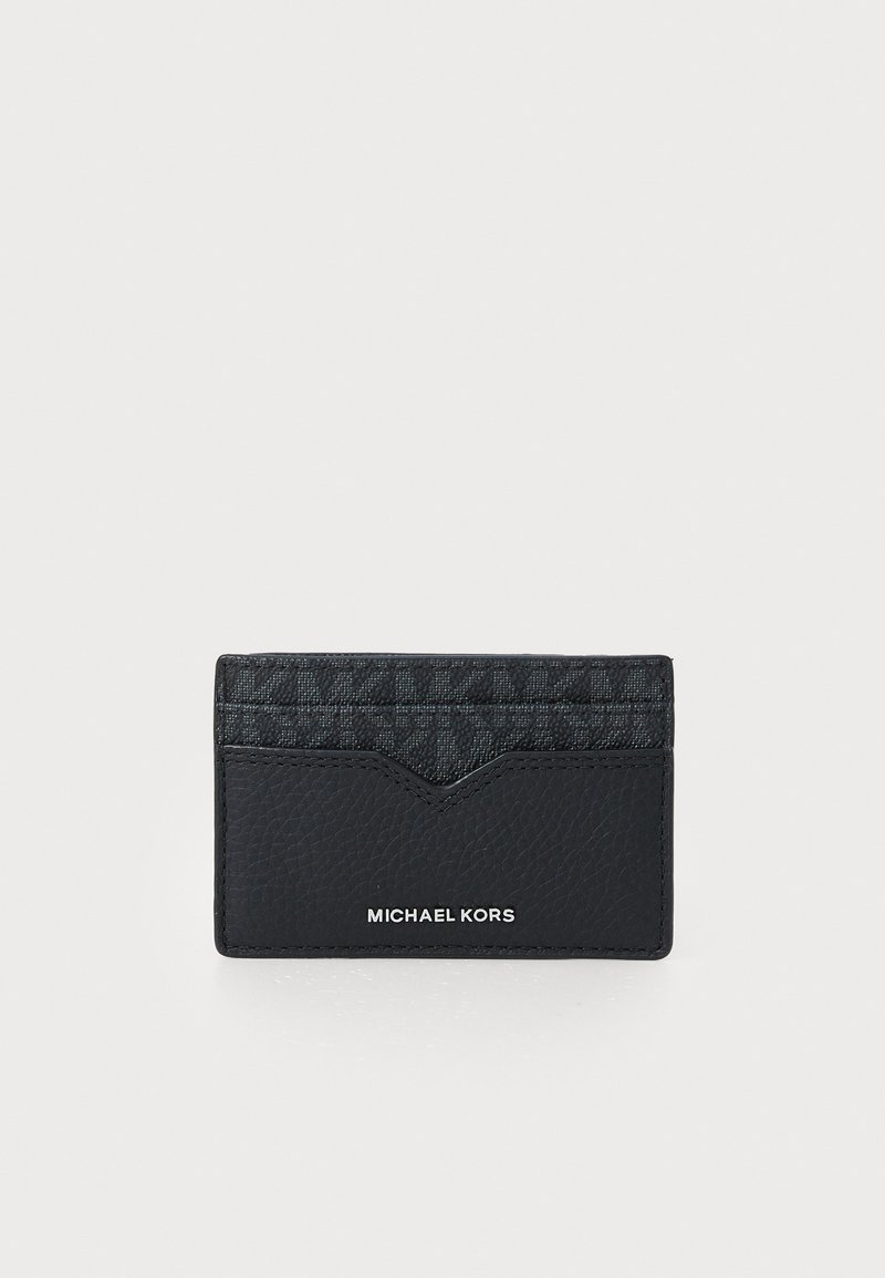 Crni kožni novčanik za kartice s teksturiranim gornjim dijelom i dizajnom u obliku chevrona. Sadrži utisnuti logo "MICHAEL KORS" na dnu.