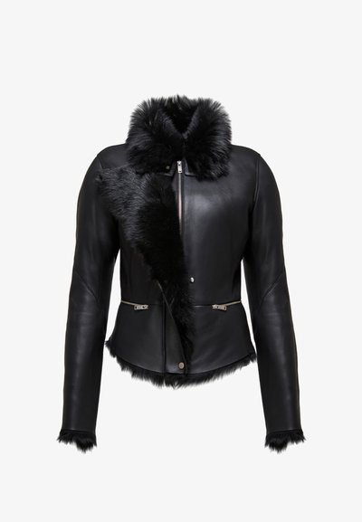 Fekete bőrkabát szőrme gallérral és elülső díszítéssel, testhez simuló fazonban, ezüst cipzárokkal és textúrált szőrme díszítéssel az alján.