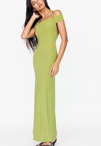 Robe maxi verte moulante avec des bretelles dénudées et un détail torsadé autour de l'encolure. Tissu lisse et extensible.