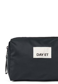 Borsa in tessuto nero dalla forma rettangolare, con un'etichetta bianca che reca la scritta "DAY ET" in nero. Chiusura con zip nella parte superiore. Superficie texture.