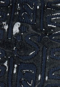 Navy fabric with textured dark letters, featuring a soft, plush surface and subtle white accents throughout the design.