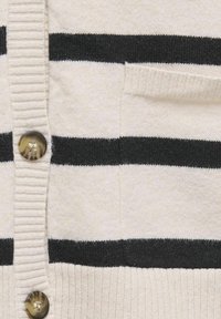 Slonasti kardigan s črnimi horizontalnimi črtami; z rebrasto teksturo, velikimi gumbi in žepom na levi strani.