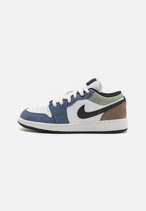 Baskets basses avec des panneaux blancs, bleus, verts et marron, swoosh Nike noir, lacets blancs et semelle noire sur fond uni.