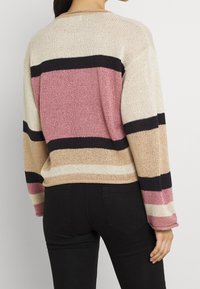 Maglione lavorato a maglia con righe orizzontali in tonalità di rosa, crema e nero. Vestibilità ampia con spalle basse e polsini a coste.