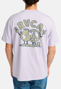 Camiseta de manga corta lila con un diseño gráfico de un globo sonriente y un signo de paz en amarillo y marino. Tejido suave con un corte holgado.