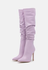 Bottes montantes lavande en matériau synthétique lisse avec un design détendu, bouts pointus et talons aiguilles élancés.