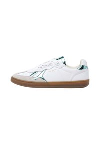 Valged tennisjalatsid tehalde aktsentidega, sile naha pealispind, hall suede varvas, ja kummist talle. Omab lamedaid paelu ja diskreetset brändi logo.