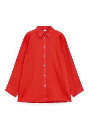Rød skjorte med lange ærmer, knapper og spids krave, lagt fladt på en hvid baggrund.
