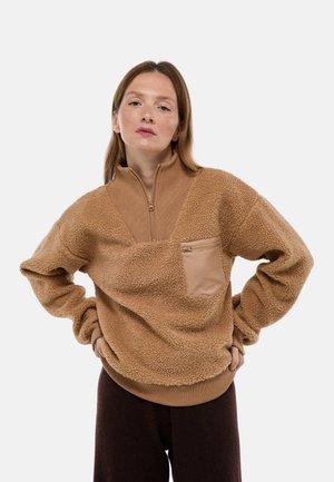 Pull en polaire marron avec un col zippé quart, poche à rabat, poignets et ourlet côtelés ; surface texturée et tissu doux.