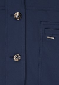 Marineblaue Jacke mit Knopfverschluss, metallischen Knöpfen und einer Brusttasche mit der Aufschrift "DRYMASTER." Glatter, strapazierfähiger Stoff.