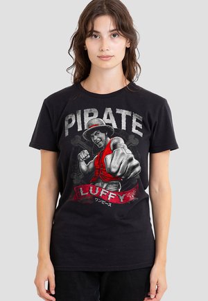 Woman wearing black T-shirt with a graphic of a pirate character punching forward, with the texts "PIRATE" and "LUFFY" in red and white.