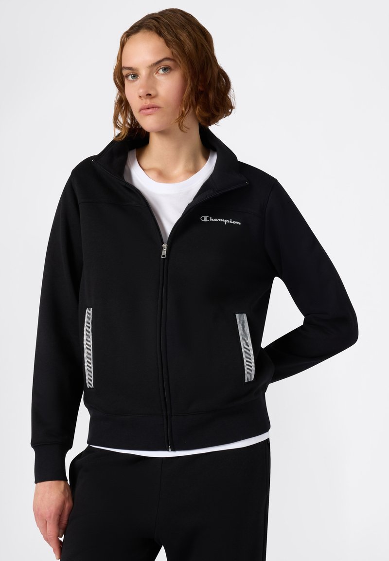 Zwart ritsvest met geribbelde kraag en manchetten, met een grijs Champion-logo op de borst en contrasterende zijzakken met streep.