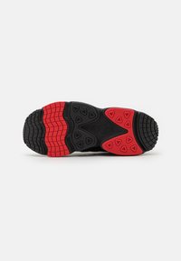 Black and red sneaker outsole with a textured pattern, featuring raised triangular accents and a distinct tread design for traction.
