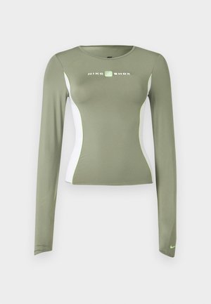 Olivengrønn Nike Shox langermet topp med hvite sidepaneler og neon grønne detaljer, tettsittende passform og liten swoosh-logo på ermekanten.
