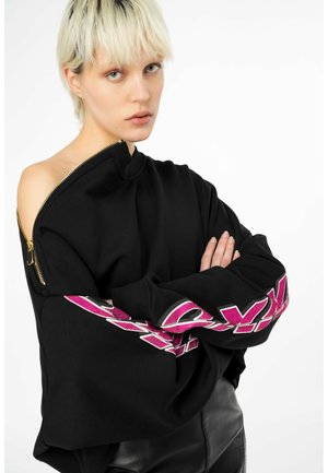 Felpa oversized nera con zip sulla spalla e testo rosa decorato lungo la manica. Texture liscia, taglio casual.