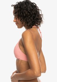 Roze textuur bikini top met een driehoekig ontwerp, verstelbare strik achter, en een open rug, die een wafelachtige structuur laat zien.