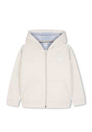 Veste à capuche crème zippée, manches longues, poches avant et doublure intérieure bleu clair visible.