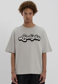 Γκρίζο κοντομάνικο T-shirt με υφή και ασπρόμαυρο γραφικό 'Lowlights' μπροστά. Φτιαγμένο από μαλακό βαμβακερό ύφασμα. Χαλαρή γραμμή.