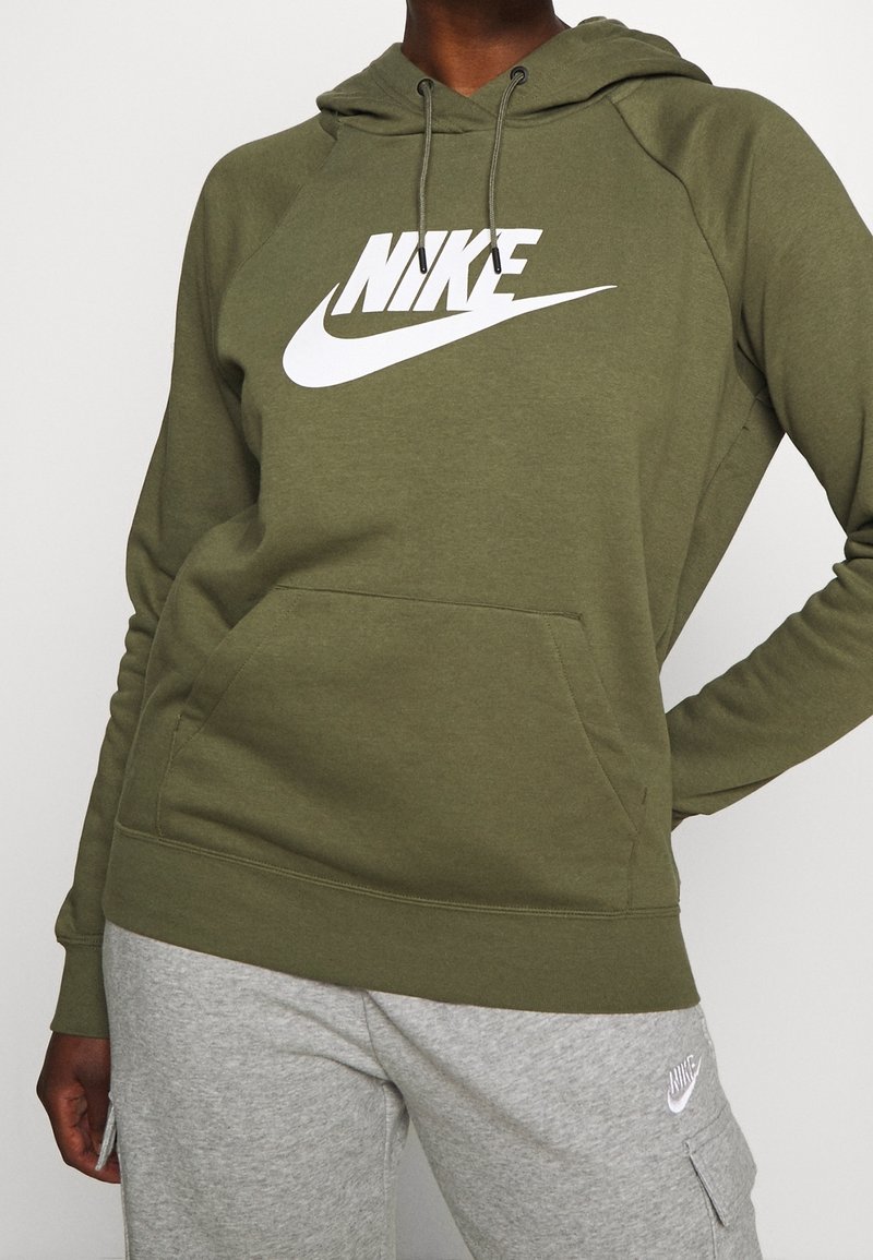 Olivgrön huvtröja med en stor vit Nike-logga, utrustad med en känguruficka, dragsko i huvan och ribbade muddar och fåll.