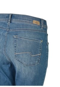 Modré džíny z denimu s zadní kapsou s bílým švem a béžovou značkovou etiketou poblíž pásku. Regular fit design.