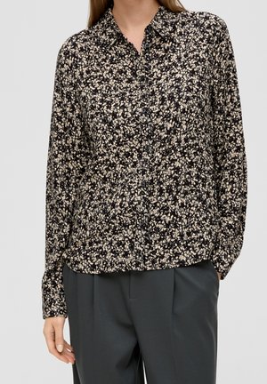 Blouse noire à boutons avec des manches longues, ornée d'un motif floral dense en crème et jaune pâle. Tissu léger, coupe décontractée.