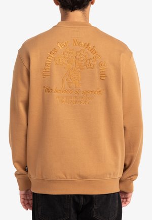 Sudadera color marrón claro con un cuello alto, que presenta texto bordado y una mano sosteniendo flores en la parte posterior. Puños y dobladillo acanalados.
