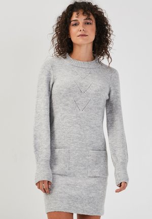 Robe en tricot grise avec manches longues, poignets côtelés et col rond. Elle dispose de deux poches frontales et de motifs triangulaires décoratifs.