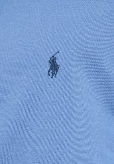 Šviesiai mėlynas polo marškinėliai su tamsiai mėlynu siuvinėtu polo žaidėjo logotipu kairėje krūtinės pusėje. Pagaminti iš tekstūruoto medvilnės audinio.